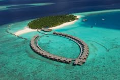 an island in the middle of the ocean with huts on it's sides and water