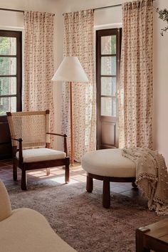 a living room with two chairs and a footstool in front of the window