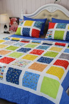 a bed with colorful quilts and pillows on it