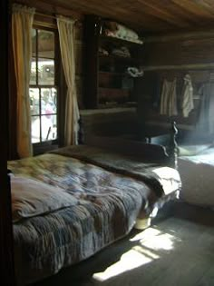 a bed sitting in a bedroom next to a window with sun shining through the curtains