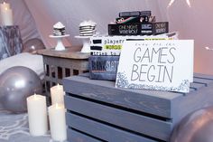 a wooden box with a sign that says games begin next to candles and other items