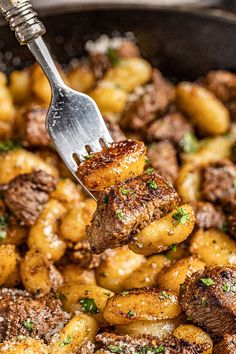 a close up of a fork with food on it in a skillet filled with potatoes