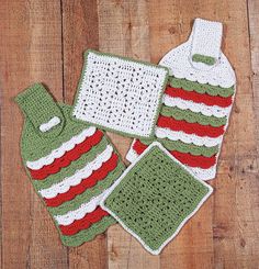 four crocheted items are laid out on a wooden surface, including a bottle and dishcloth