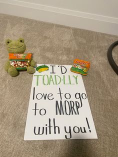 a stuffed frog sitting next to a sign that says i'd toadly love to go to morp with you