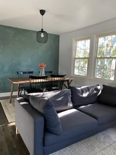 a living room filled with furniture next to a dining room table and two large windows