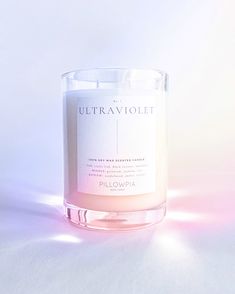 a lit candle sitting on top of a white table next to a pink and blue background