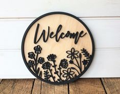 a wooden sign that says welcome with flowers