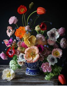 an arrangement of flowers in a blue and white vase on top of a wooden table