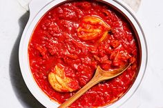 a white bowl filled with red sauce next to a wooden spoon