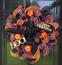 a halloween wreath with black mesh and orange pumpkins on the front door for trick or treat