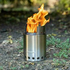 a metal fire pit sitting on top of a forest floor