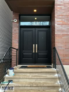 two black doors on the side of a brick building with steps leading up to it