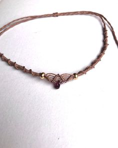 a brown string with beads and a bead on the end is sitting on a white surface