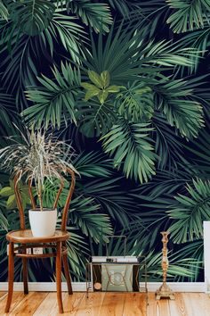 a chair and potted plant in front of a wall with palm leaves on it