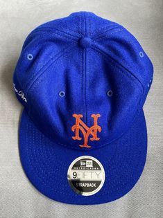 ALD x New Era wool 9FIFTY strapback hat in classic New York Mets blue with orange NY logo. Leather strap and Aime Leon Dore embroidered logo on the right side of the hat. ALD x New Era label on the inside of hat. Retro style green underbill. Classic Blue Hats For Sports Events, Classic Blue Hat For Sports Events, Adjustable Short Brim Fitted Hat For Sports Events, Short Brim Baseball Cap For Baseball Season, Classic Blue Baseball Cap With Flat Brim, Casual Blue Felt Hat With Flat Brim, Blue Sports Hat With Short Brim, Blue Visor Fitted Hat For Baseball Season, Blue Short Brim Sports Hat