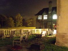 there are many chairs and tables outside on the grass near a building at night time