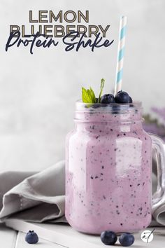 a blueberry protein shake in a mason jar with a striped straw and mint sprig