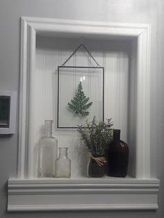 a shelf with vases and bottles on it in a room that is painted white