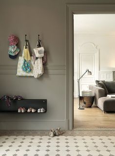 a living room filled with furniture and lots of shoes hanging on the wall next to a couch