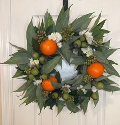 a wreath with oranges and white flowers hanging on a door handle next to a doorway