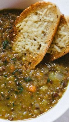 two pieces of bread sticking out of a bowl of soup