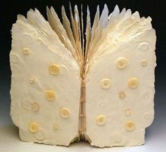 an open book with buttons on it and the pages are made out of white paper