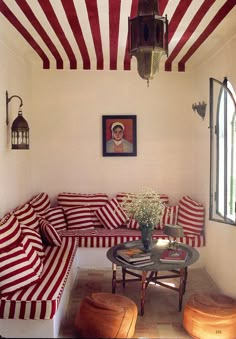 a red and white striped couch in a room next to a table with flowers on it