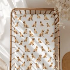 a baby's crib with small dogs on it, next to a wicker basket