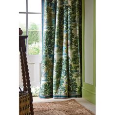 a window with green curtains in front of it and a rug on the floor next to it