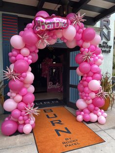 a pink balloon arch decorated with starbursts and balloons