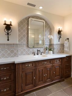 a bathroom with two sinks, mirrors and lights on the wall above them is shown