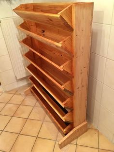 a wooden shelf with several compartments on the top and bottom, in front of a tiled wall