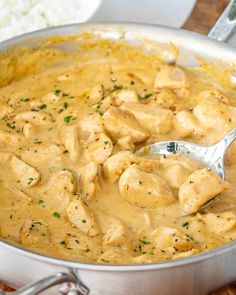 a pan filled with chicken and gravy on top of a wooden table