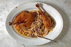 a white plate topped with meat and gravy on top of a marble counter