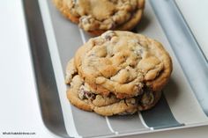 three chocolate chip cookies sitting on top of a metal tray