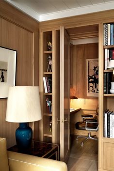 a living room filled with furniture and bookshelves next to a lamp on a table