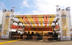 an outdoor stage set up for a concert with banners on the sides and lights at the top