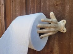 a hand that is sticking out of a roll of toilet paper on a wooden wall