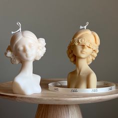 two small figurines sitting on top of a wooden tray