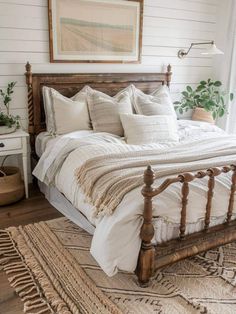 a bed with white linens and pillows in a bedroom next to a painting on the wall