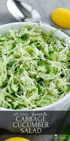 a white bowl filled with shredded cucumbers and lemons next to green onions