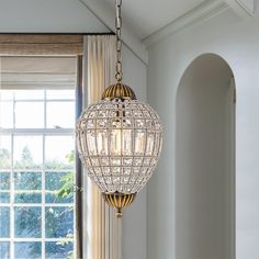 a chandelier hanging from the ceiling in a living room with windows and curtains