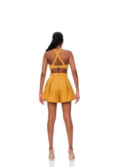 the back view of a woman wearing a short yellow dress with cutouts on it