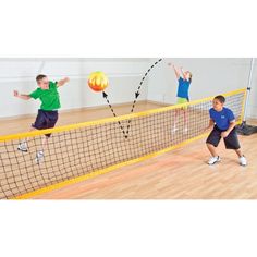 three young boys are playing tennis on an indoor court