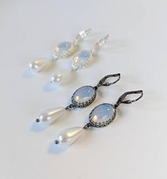 This listing is for a pair of earrings made with gorgeous vintage glass Moonstones. They are amazingly bright and reflective- some of the loveliest stones I have ever worked with!  I've set them in my favorite crown prong settings for lots of visual interest and luxury.  A high-quality glass pearl dangles from the stone. They are available in Antique Silver, Silver, and Gold.   The settings are plated brass, nickel free! They are also available with hinge-back clip-on findings.  The total length Historical Jewellery, Moonstone Earrings, Victorian Jewelry, Earrings Vintage, Moon Stone, Silver And Gold, Vintage Earrings, Moonstone, Antique Silver