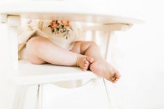 a baby sitting in a high chair with its foot on the edge of it's seat