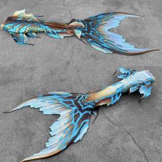 two large blue and gold fish laying on the ground next to each other in concrete