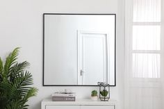 a white dresser topped with a mirror next to a potted plant