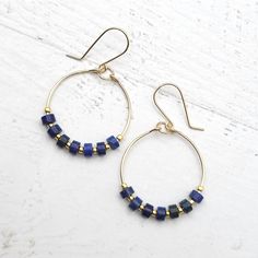 Add a touch of bohemian charm with our Boho hoop earrings featuring Lapis Lazuli beads. These 14k Gold Filled hoops offer effortless style and a pop of color to any outfit. 14k Gold Filled Wire Measure approximately 1.125" in diameter Earrings Hang 1.75" from top of ear wire Lapis Lazuli Gemstones Polished to a high shine Sent in a Gift Box with Polishing Cloth Handmade in Montana Everyday Small Hoop Jewelry With Dangling Beads, Boho Hoop Earrings, Lapis Lazuli Beads, Gold Filled Hoops, African Turquoise, Jewelry Packaging, Ear Wire, Lapis Lazuli, Guatemala