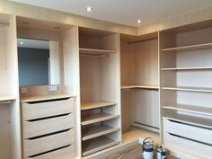 an empty walk in closet is shown with white cabinets and drawers on either side of the closet